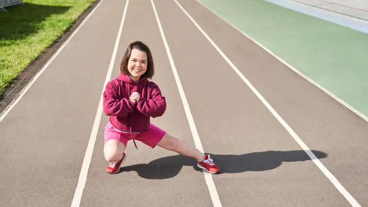 Jugendliche mit Achondroplasie macht Dehnübungen in einem Stadion